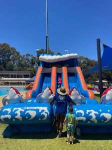 A large, blue inflatable water slide named 'Ocean Splash' at an outdoor event in Claremont.