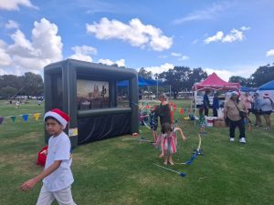 People gathered near a dark-colored food truck at a festival in South Perth Foreshore.