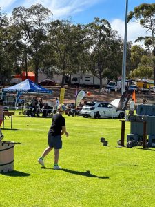 A boy throwing a ball at an outdoor game stall at a community event in