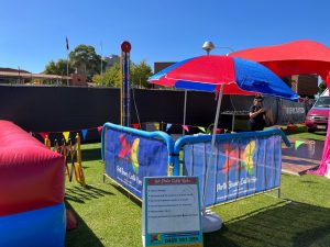 A person using a mallet to play a classic "hi-striker" strength-testing game at an event in Bentley.