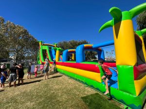 A vibrant, tropical-themed inflatable water slide named "Tropical Thunder" at an event in Mandurah.